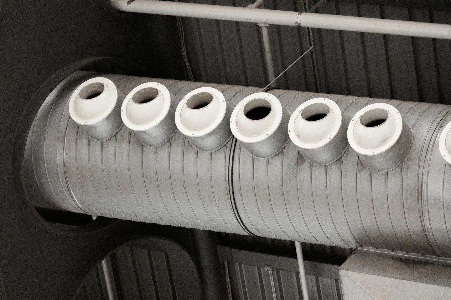 Condotti di ventilazione in metallo con diffusori circolari su un soffitto.